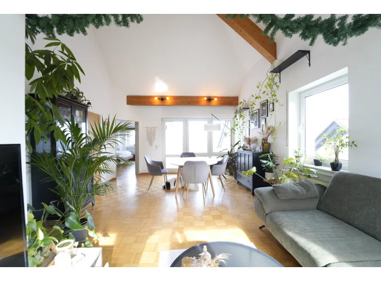 lichtdurchflutetes Wohnzimmer mit hoher Decke und Zugang zum Balkon